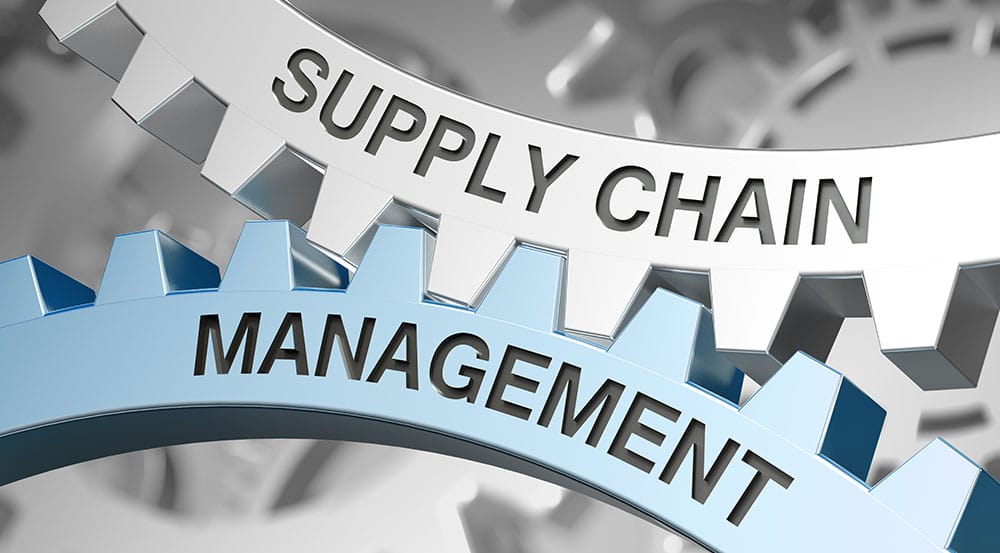 Close-up of two interlocking gears. The top gear is labeled "SUPPLY CHAIN" and the bottom gear is labeled "MANAGEMENT." The metallic shades emphasize the connection and integration of supply chain, supplier management, and overall management processes.