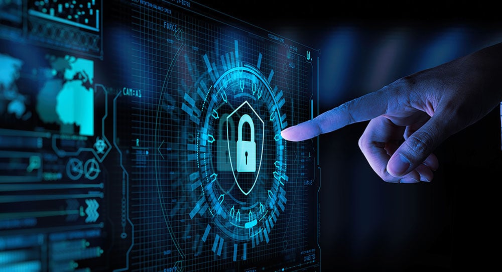 A hand points to a digital screen displaying a padlock icon surrounded by a circular interface, indicating a focus on cybersecurity solutions. The screen features various data, charts, and graphs in a blue, futuristic theme.