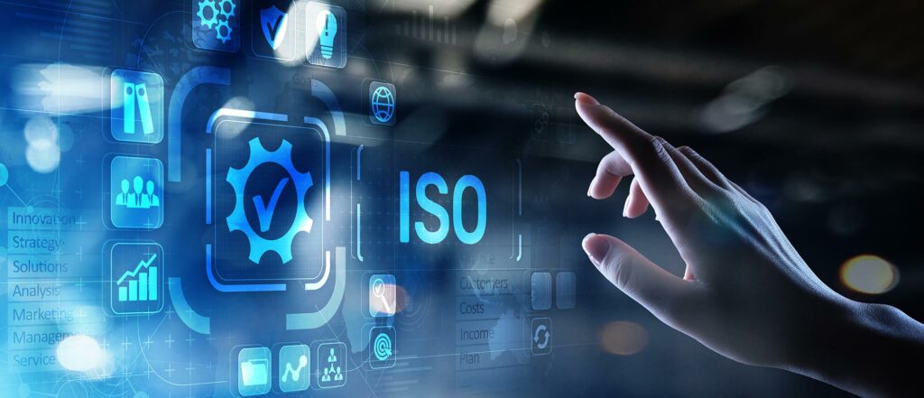 AdobeStock_311178099-web - JVR Consultancy A hand reaches towards a digital interface adorned with the text "ISO" and various icons representing business concepts such as marketing, solutions, analysis, strategy, and more—all illuminated in a futuristic blue glow—highlighting the essence of ISO 9001 certification in quality management.