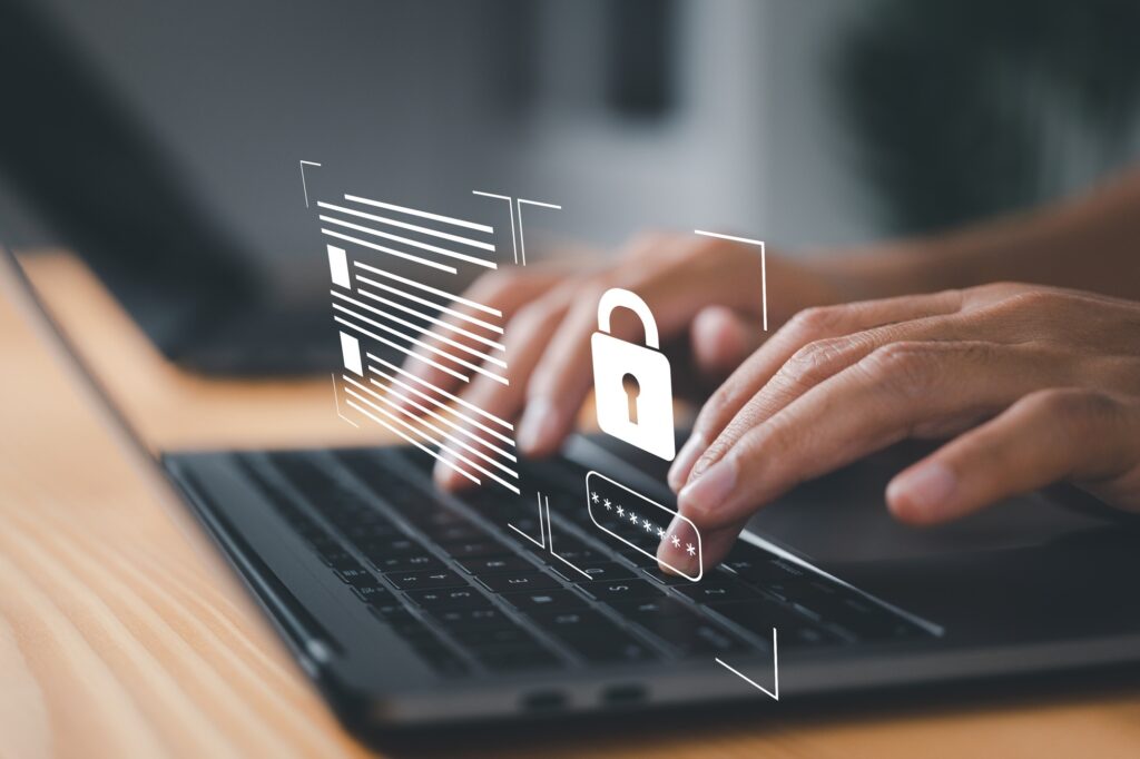Hands typing on a laptop keyboard with a holographic padlock icon overlay, symbolizing cybersecurity and data protection—a crucial step for organizations aiming to become SSIP Accredited.
