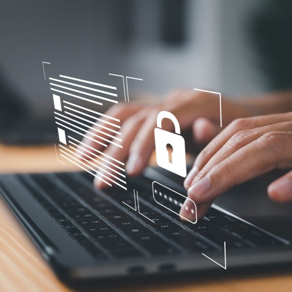 Hands typing on a laptop keyboard with a holographic padlock icon overlay, symbolizing cybersecurity and data protection—a crucial step for organizations aiming to become SSIP Accredited.